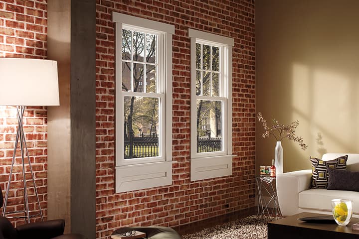 Modern living room with exposed brick walls and white French doors overlooking trees