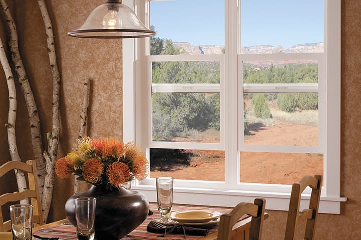 Modern dining room with scenic desert mountain view through large windows and floral centerpiece
