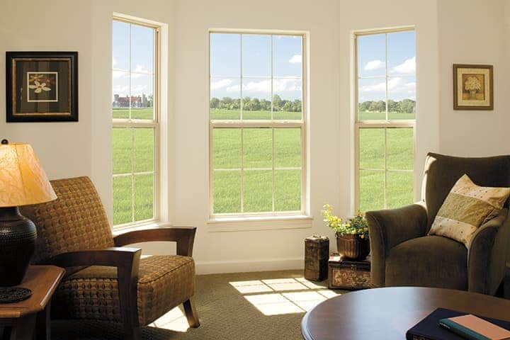 Modern living room with large windows overlooking green countryside fields and comfortable seating