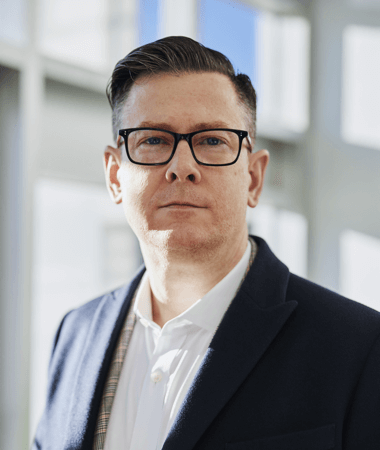 Professional business headshot of male executive in office setting