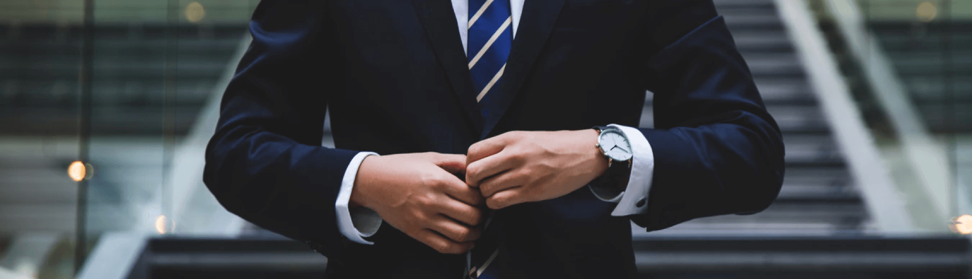 Professional businessman in navy suit adjusting jacket in modern office building