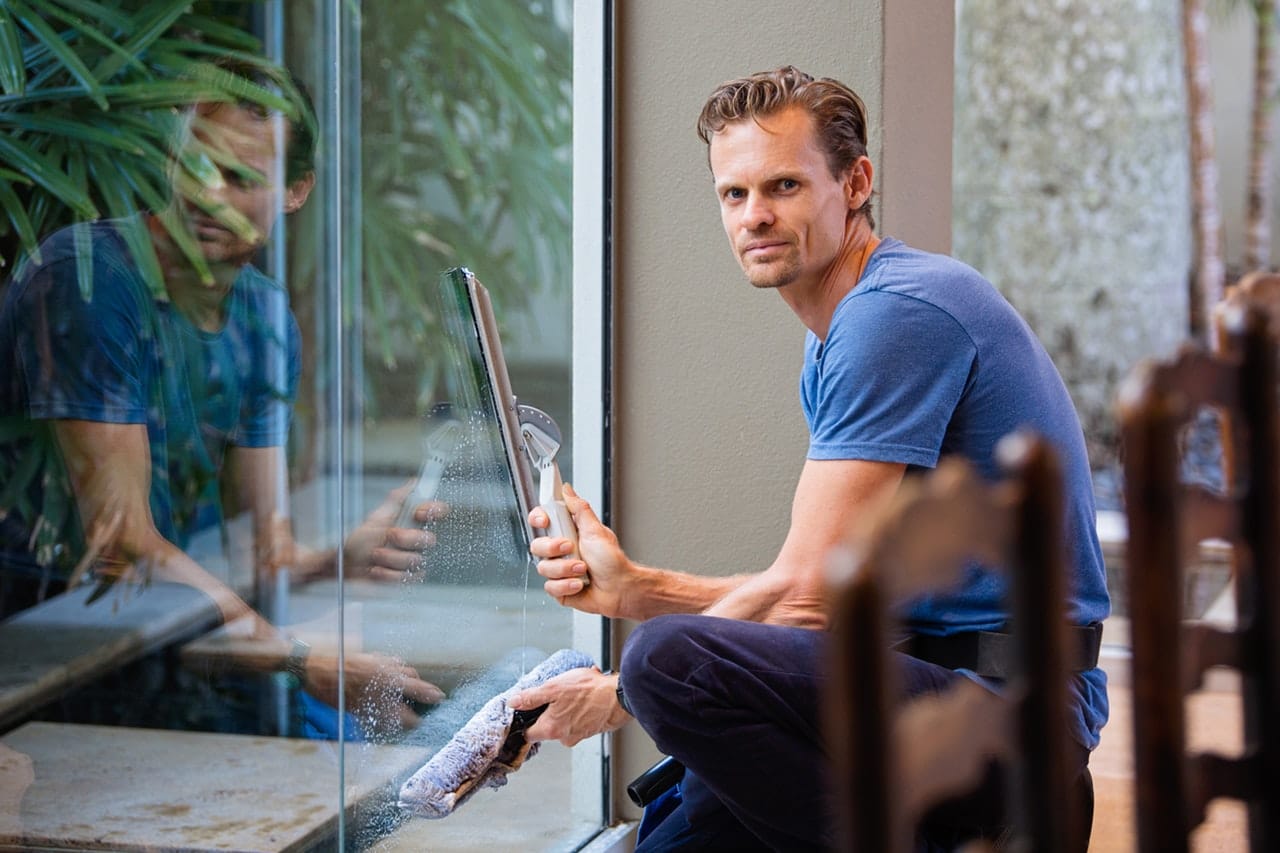 Professional window cleaner using squeegee on glass storefront