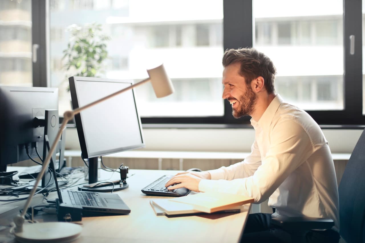 Professional man working at computer in bright modern office with city view