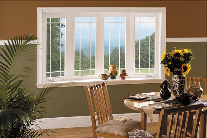 Bright interior with large windows overlooking mountains, wooden furniture, and sunflowers