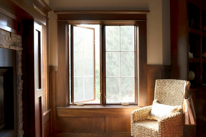 Bright interior room with wooden-framed windows and cozy rattan armchair in natural sunlight