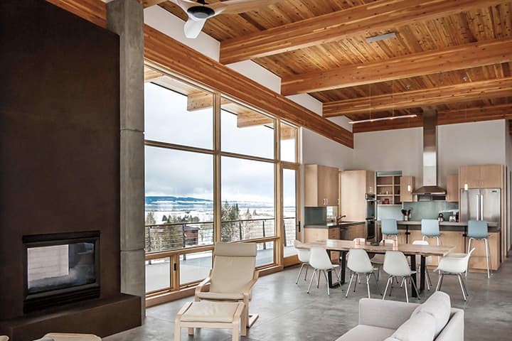 Modern open-concept home with lake view, wooden beams, and floor-to-ceiling windows