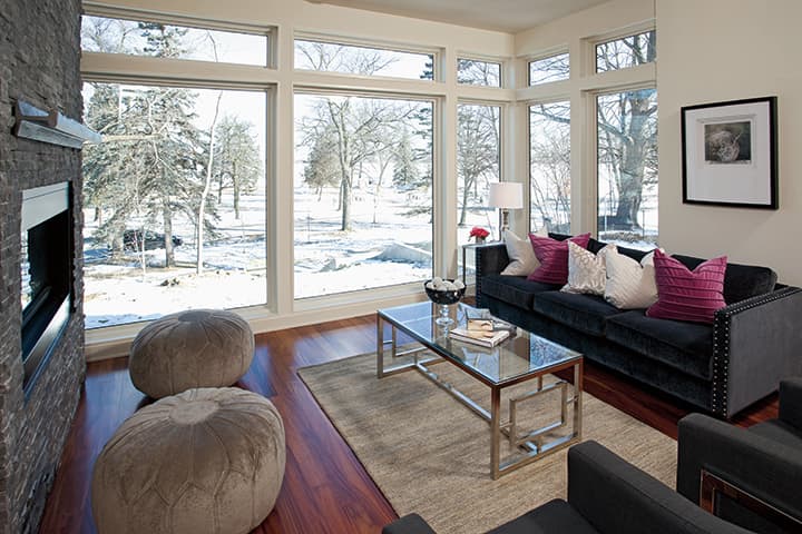 Modern living room with black sofa overlooking snowy landscape through large windows