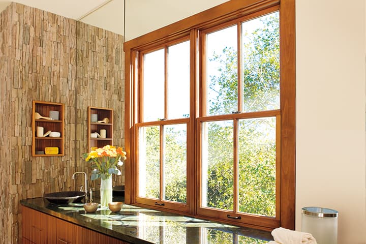 Modern kitchen with black countertop, wooden shelving, and large windows overlooking garden