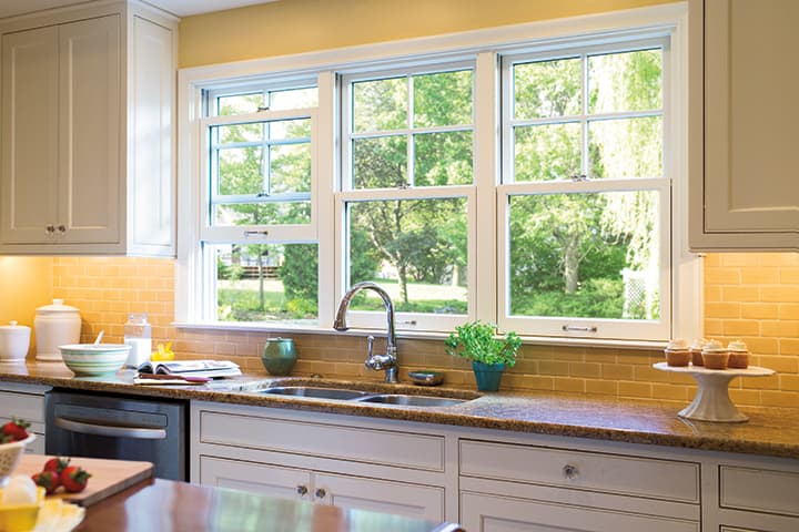 Bright modern kitchen with white cabinets, yellow tile backsplash, and garden views