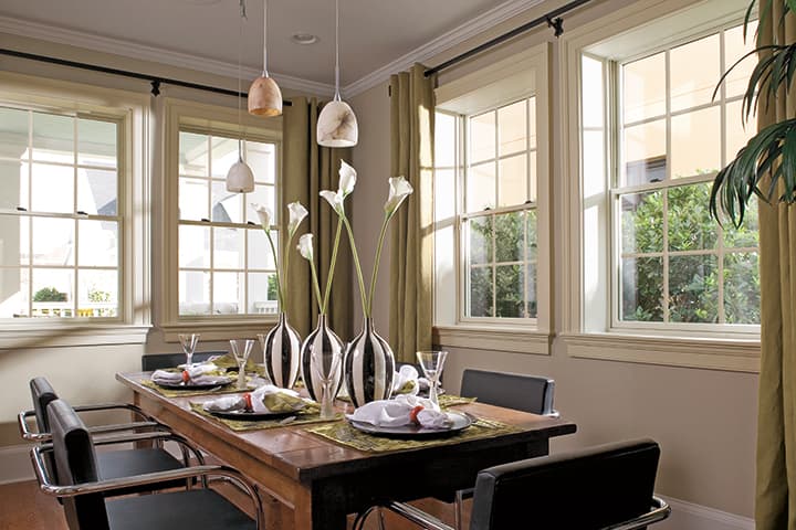 Modern dining room with wooden table, black chairs, and garden views through large windows