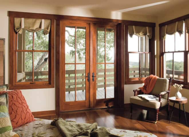 Luxury bedroom with wooden French doors and scenic landscape views through multiple windows