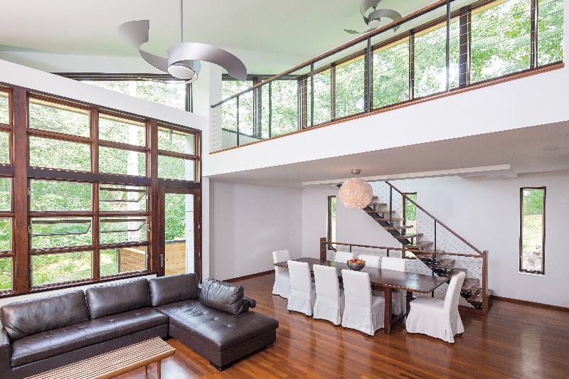Modern loft interior with high ceilings, large windows, leather sofa, and dining area