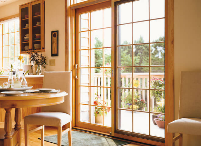 Bright dining room with wooden furniture, open French doors overlooking a garden terrace