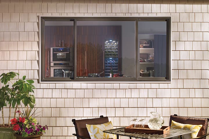 Modern patio with dining table overlooking luxury kitchen through glass windows