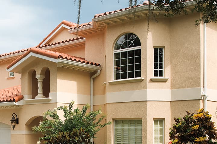 Mediterranean-style home with peach exterior, terracotta roof, and arched windows